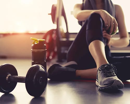 A person sitting on the ground next to a dumbbell.